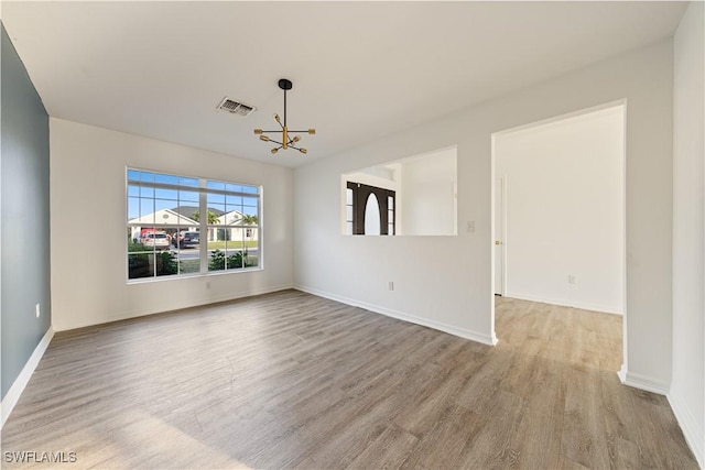 unfurnished room with a chandelier and light hardwood / wood-style floors