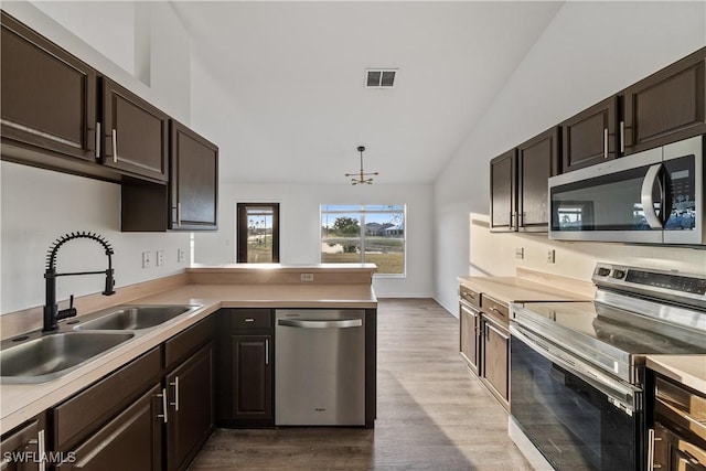 kitchen featuring vaulted ceiling, wood-type flooring, sink, kitchen peninsula, and stainless steel appliances