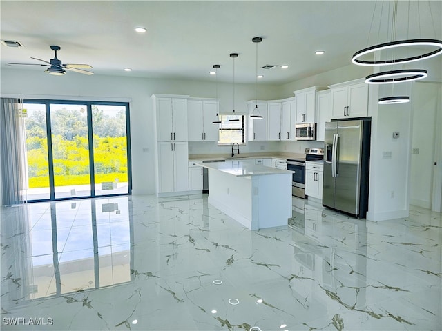 kitchen with a kitchen island, light tile patterned floors, pendant lighting, and stainless steel appliances