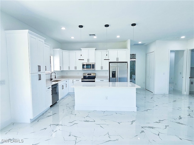 kitchen with stainless steel appliances, white cabinets, a center island, and hanging light fixtures