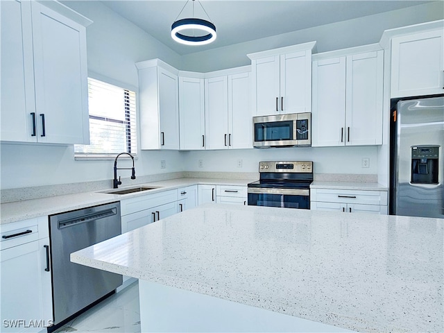 kitchen featuring hanging light fixtures, white cabinetry, light stone countertops, sink, and stainless steel appliances