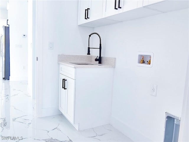 laundry room with sink, light tile patterned floors, cabinets, and hookup for a washing machine