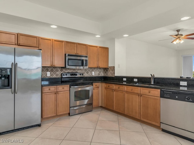 kitchen featuring sink, dark stone countertops, appliances with stainless steel finishes, ceiling fan, and decorative backsplash