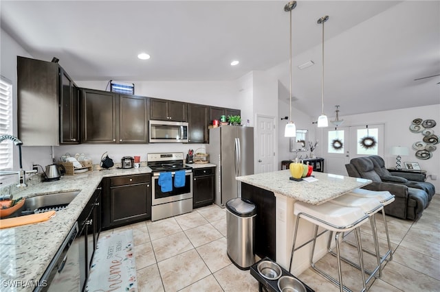 kitchen with stainless steel appliances, sink, light stone counters, a kitchen breakfast bar, and light tile patterned flooring