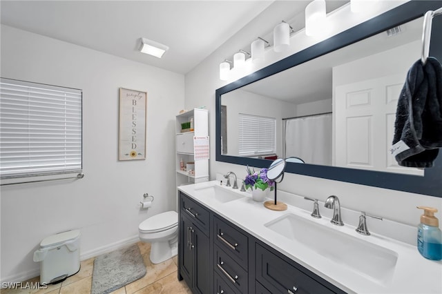 bathroom featuring toilet, double sink vanity, and tile patterned flooring