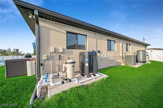 rear view of property featuring central AC unit and a lawn