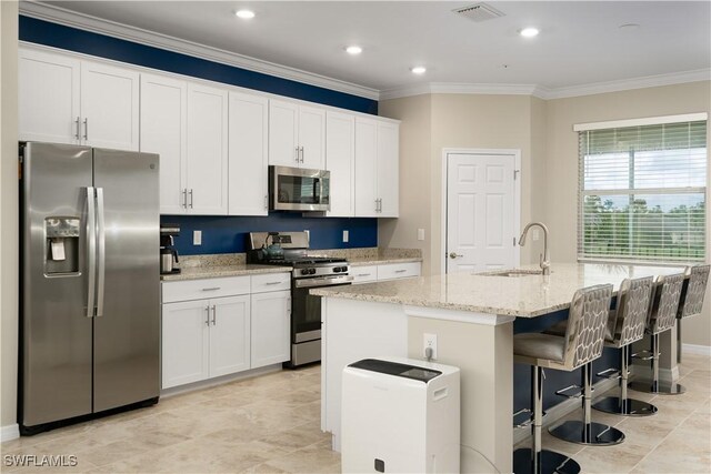 kitchen featuring a kitchen island with sink, stainless steel appliances, visible vents, white cabinetry, and light stone countertops