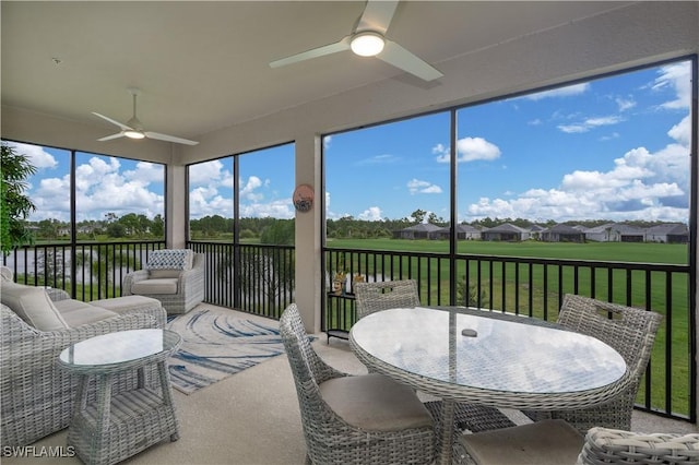 sunroom / solarium featuring ceiling fan, a water view, and a residential view