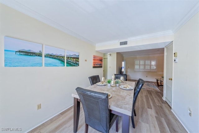 dining space featuring crown molding and light wood-type flooring