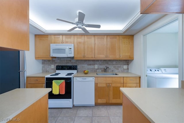 kitchen featuring washer and dryer, a tray ceiling, light tile patterned flooring, sink, and white appliances