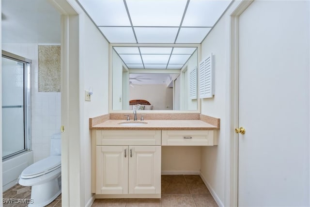 full bathroom with combined bath / shower with glass door, toilet, vanity, a drop ceiling, and tile patterned floors