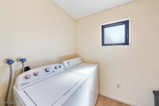 laundry area with a textured ceiling, light tile patterned floors, and separate washer and dryer