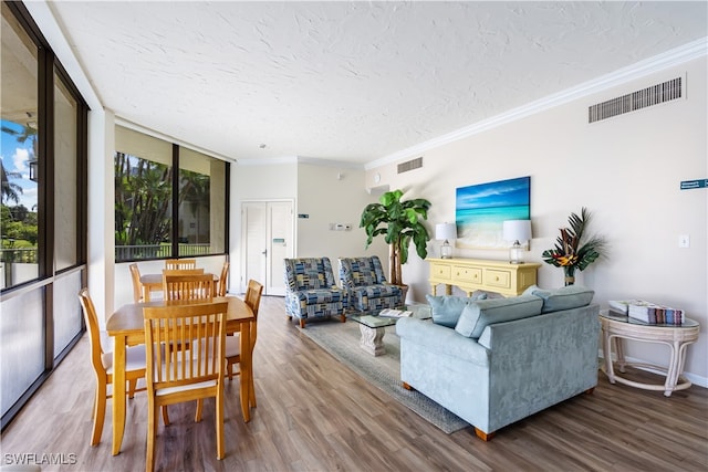 living room featuring a textured ceiling, wood-type flooring, ornamental molding, and expansive windows