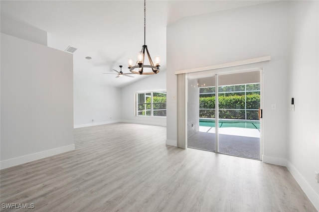 spare room with ceiling fan with notable chandelier, light hardwood / wood-style flooring, and high vaulted ceiling