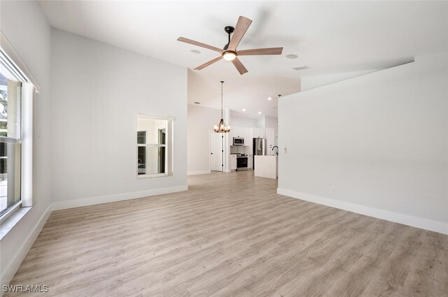 unfurnished living room with visible vents, baseboards, light wood-style floors, high vaulted ceiling, and ceiling fan with notable chandelier