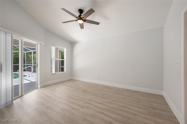 empty room with lofted ceiling, light wood-style floors, ceiling fan, and baseboards