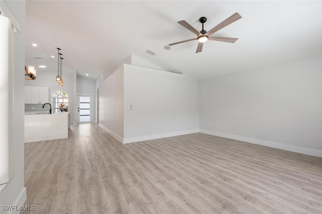 unfurnished living room with sink, vaulted ceiling, ceiling fan, and light wood-type flooring