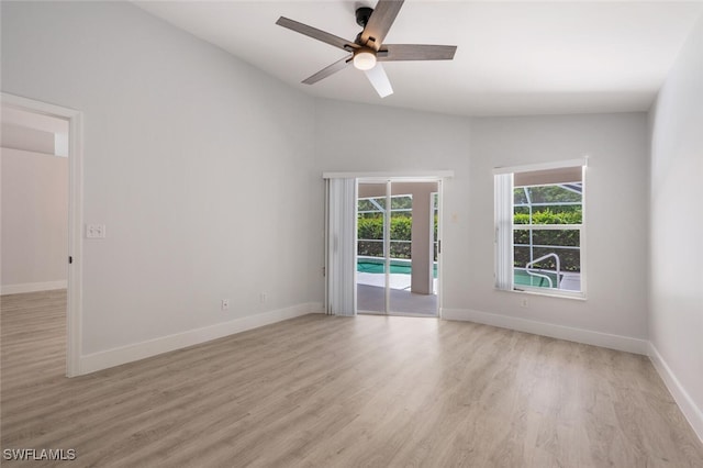 unfurnished room featuring lofted ceiling, light wood finished floors, baseboards, and a ceiling fan