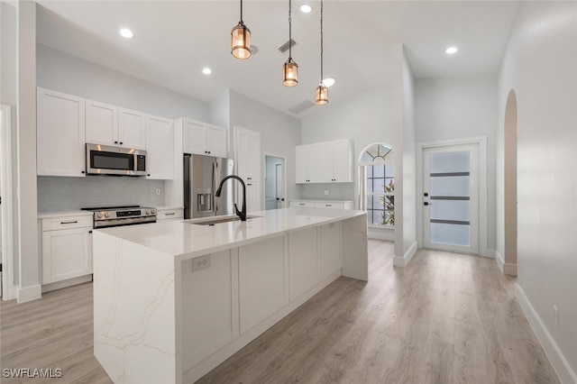 kitchen with a center island with sink, white cabinets, light hardwood / wood-style floors, appliances with stainless steel finishes, and sink