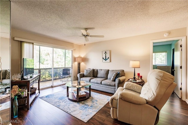 living room with ceiling fan, plenty of natural light, a textured ceiling, and dark wood-style floors