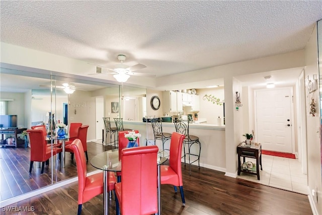 dining area with wood finished floors, a ceiling fan, a textured ceiling, and baseboards