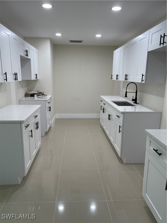 kitchen featuring light tile patterned floors, sink, and white cabinetry