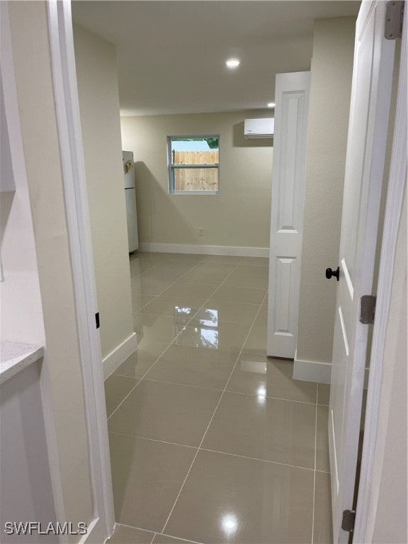 hall featuring light tile patterned flooring and an AC wall unit