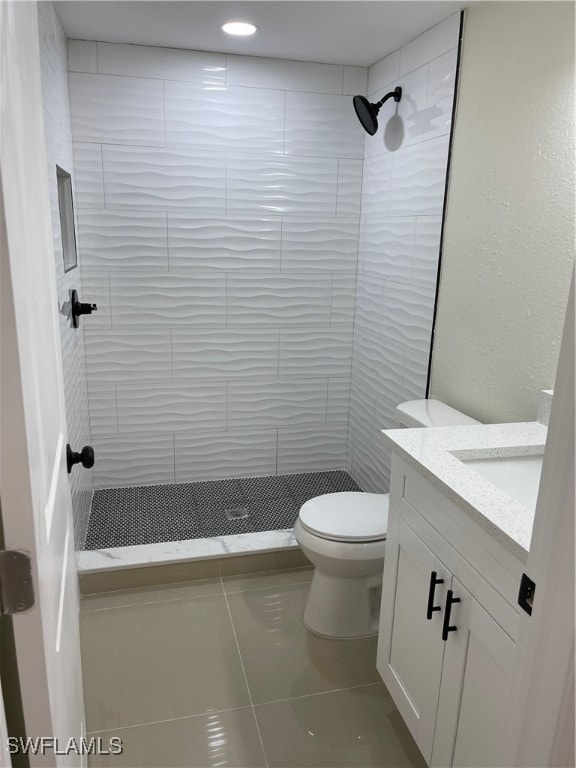 bathroom featuring tiled shower, vanity, tile patterned floors, and toilet