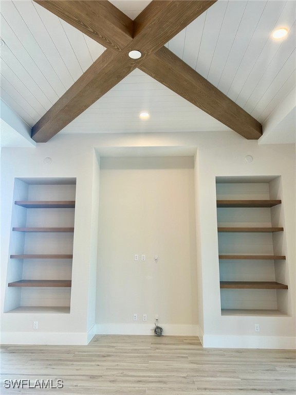 basement featuring wood ceiling, light wood-type flooring, and built in shelves