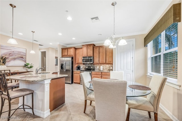 kitchen featuring appliances with stainless steel finishes, decorative backsplash, a breakfast bar, brown cabinetry, and a kitchen island with sink