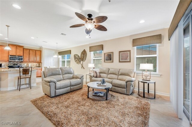 tiled living room with ceiling fan and ornamental molding