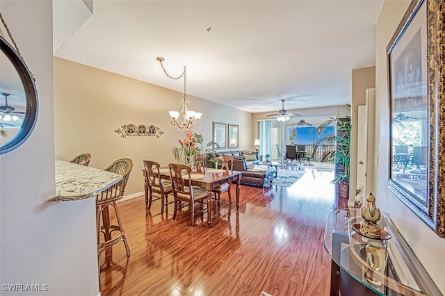 dining space featuring ceiling fan with notable chandelier and wood-type flooring