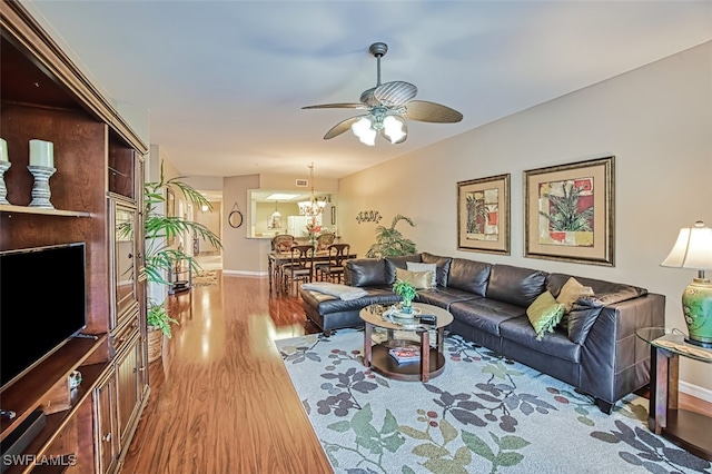 living room featuring ceiling fan with notable chandelier and hardwood / wood-style flooring