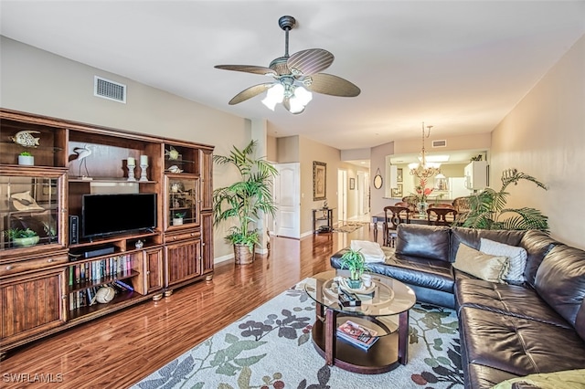 living room featuring ceiling fan with notable chandelier and hardwood / wood-style flooring