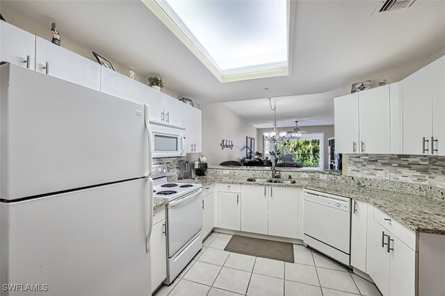 kitchen featuring white appliances, light tile patterned flooring, kitchen peninsula, and backsplash