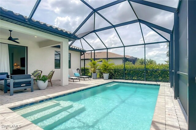 view of pool with a patio, ceiling fan, and glass enclosure