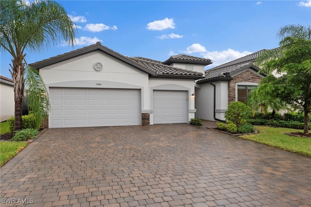 view of front of house featuring a garage, stone siding, decorative driveway, and stucco siding