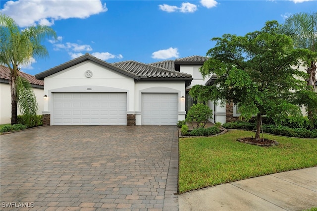 mediterranean / spanish house with an attached garage, stone siding, decorative driveway, stucco siding, and a front lawn