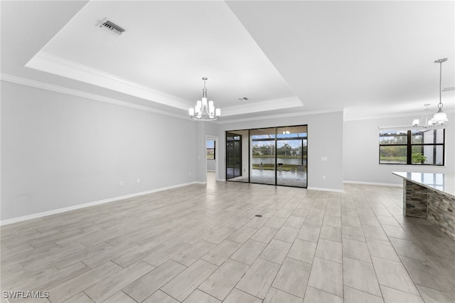 unfurnished living room featuring a tray ceiling, a wealth of natural light, and an inviting chandelier