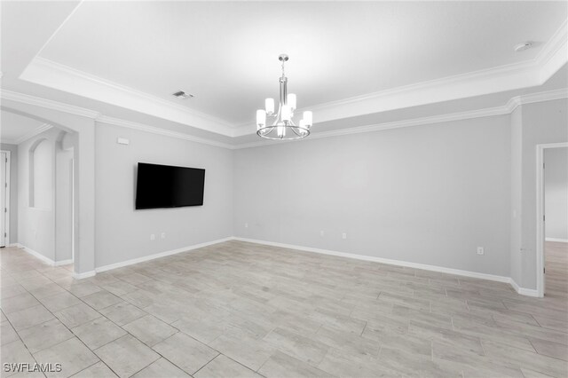 unfurnished room featuring a tray ceiling, an inviting chandelier, and ornamental molding