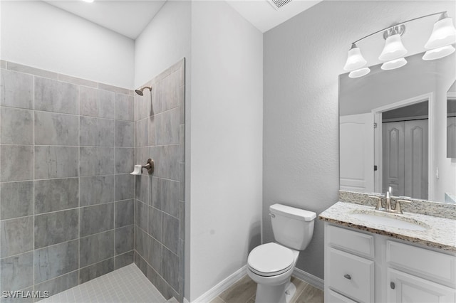 bathroom with vanity, toilet, and tiled shower