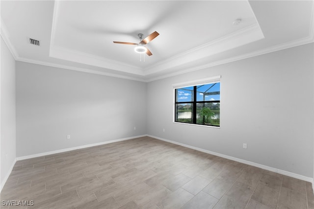 unfurnished room with a tray ceiling, ceiling fan, and crown molding