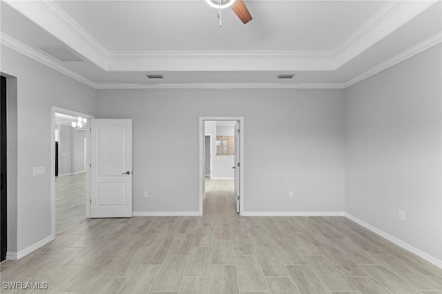 unfurnished bedroom featuring visible vents, crown molding, a tray ceiling, and baseboards