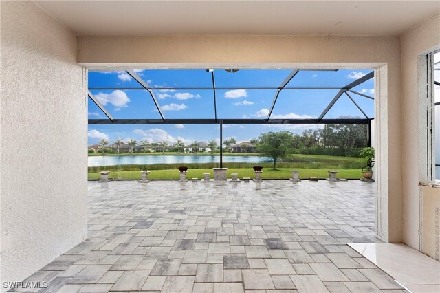 view of patio with a lanai and a water view