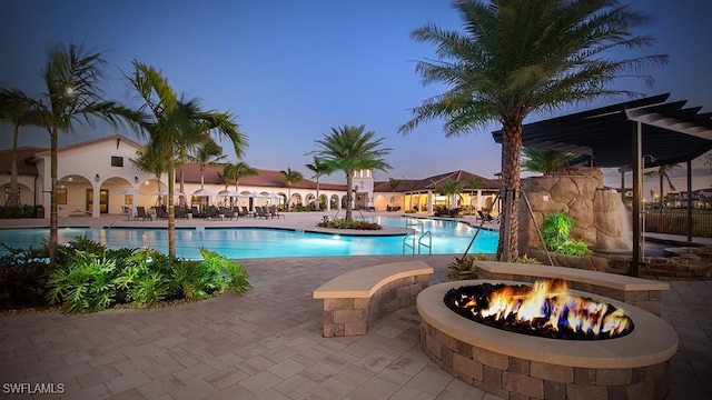 pool at dusk with a patio area and an outdoor fire pit