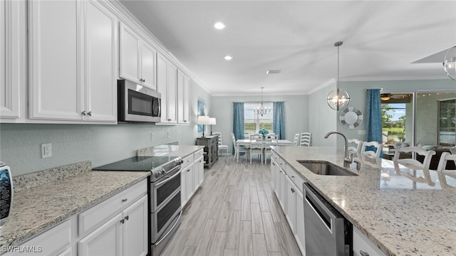 kitchen with stainless steel appliances, light stone countertops, a chandelier, ornamental molding, and sink