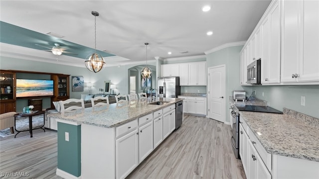 kitchen with hanging light fixtures, appliances with stainless steel finishes, a center island with sink, ceiling fan, and sink