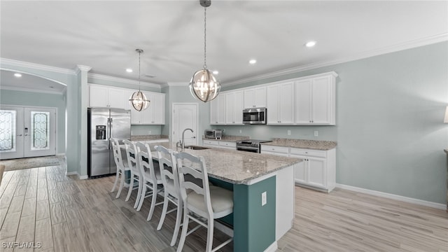 kitchen featuring stainless steel appliances, ornamental molding, light hardwood / wood-style floors, and white cabinetry