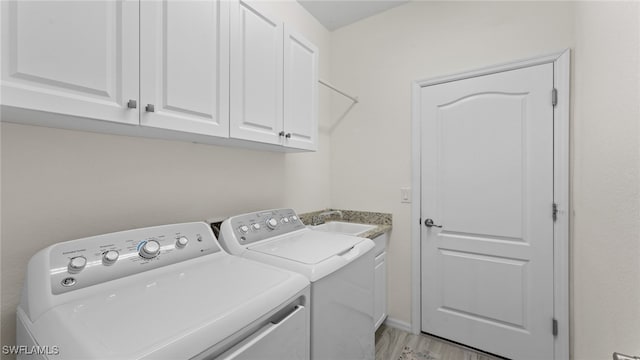 laundry room featuring light wood-type flooring, washing machine and dryer, cabinets, and sink