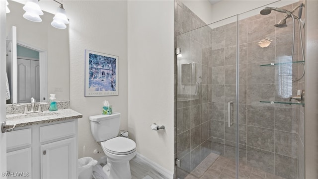 bathroom featuring a shower with door, vanity, and toilet